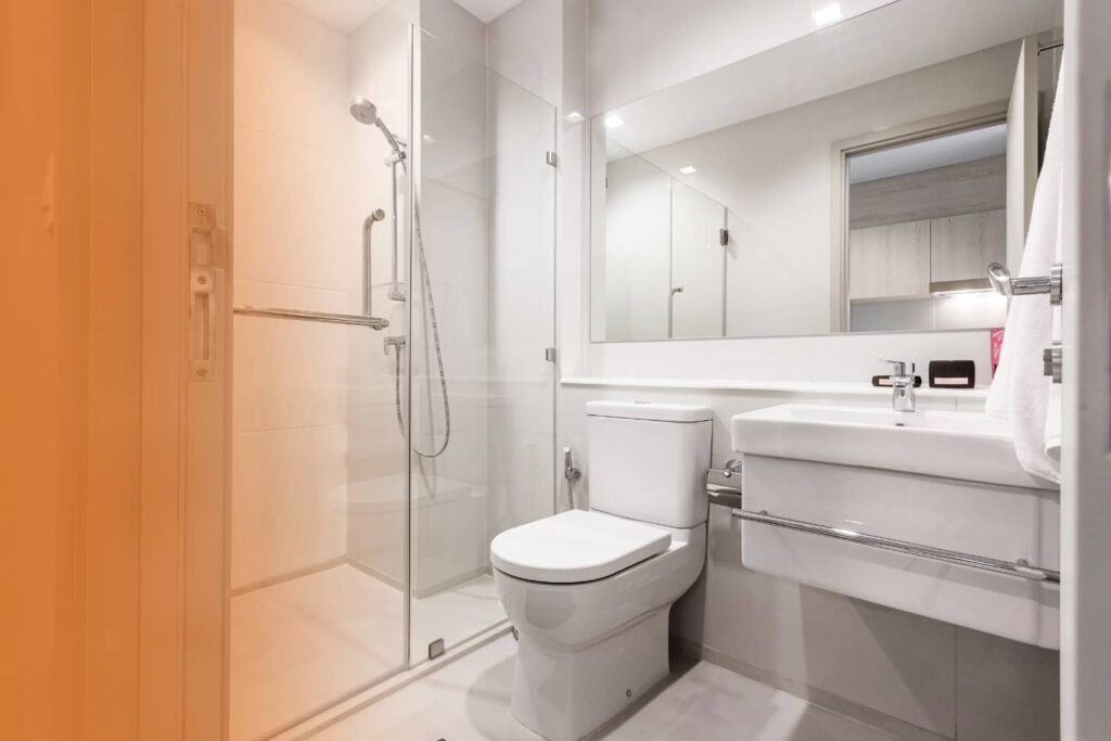 A clean, modern bathroom featuring a white toilet positioned next to a glass-enclosed walk-in shower.