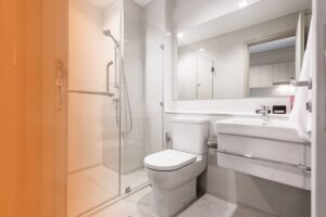 A clean, modern bathroom featuring a white toilet positioned next to a glass-enclosed walk-in shower.