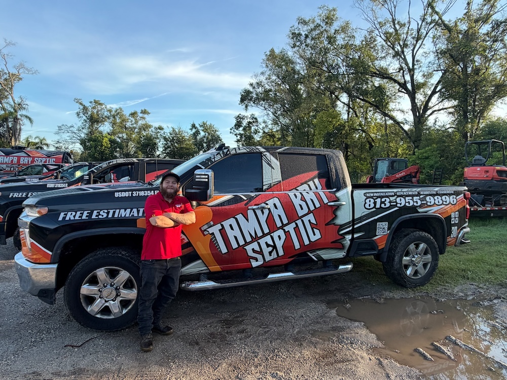 A technician stands beside a branded Tampa Bay Septic service truck equipped for septic tank repair tampa fl.